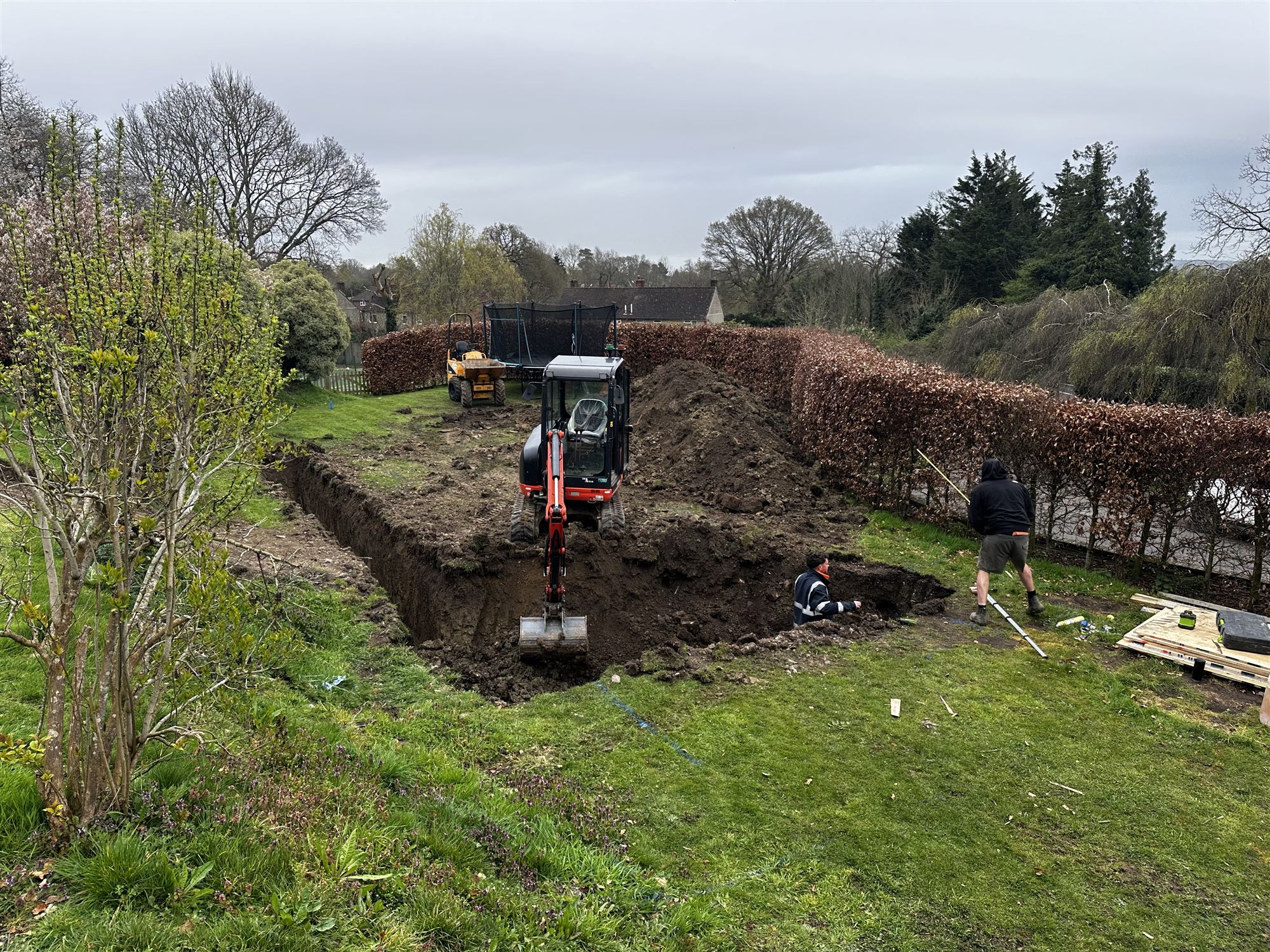 Excavator beginning the pool dig in the lawn