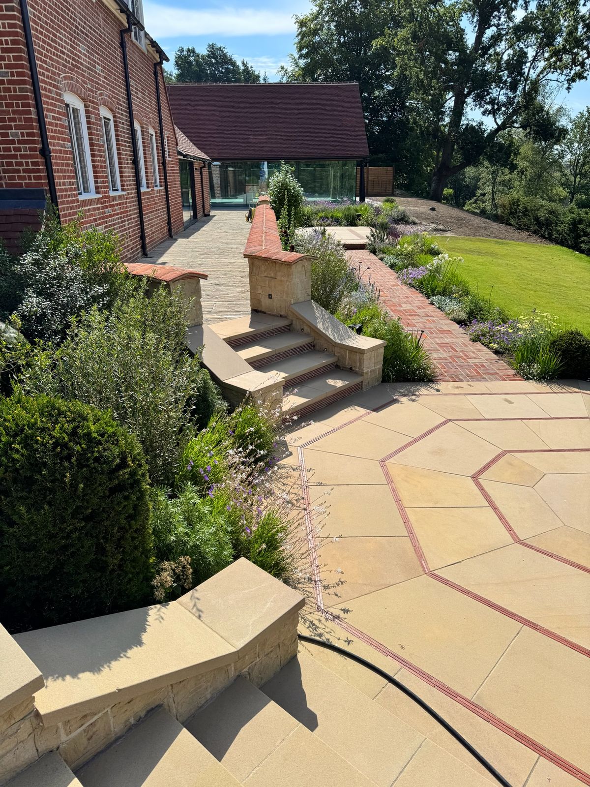 Designer-led formal garden with sandstone paving and raised stone planters