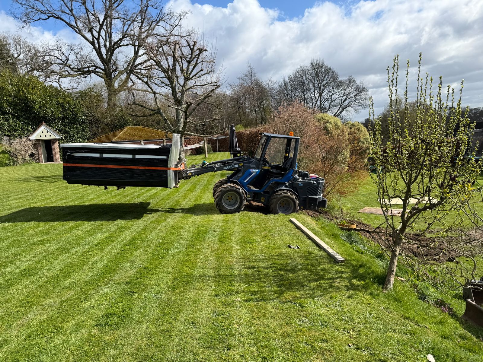 Compact loader moving materials across a lawn