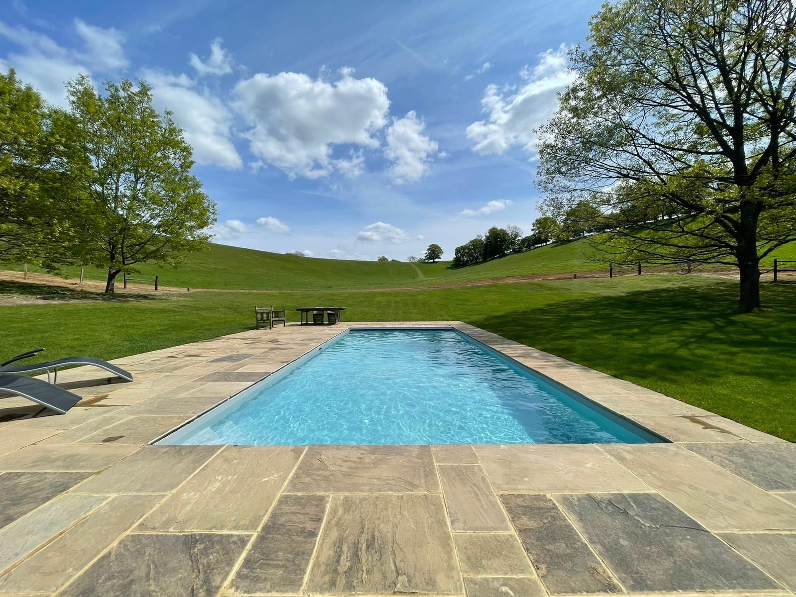 Finished swimming pool with stone surround overlooking open countryside