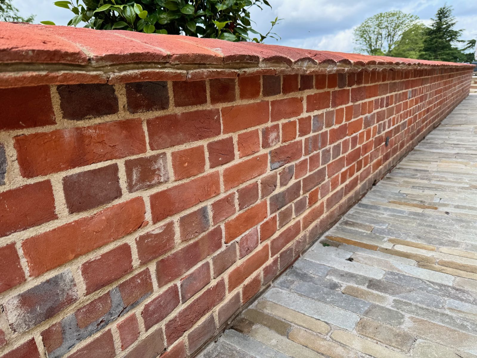 New brick garden wall with coping alongside stone paving